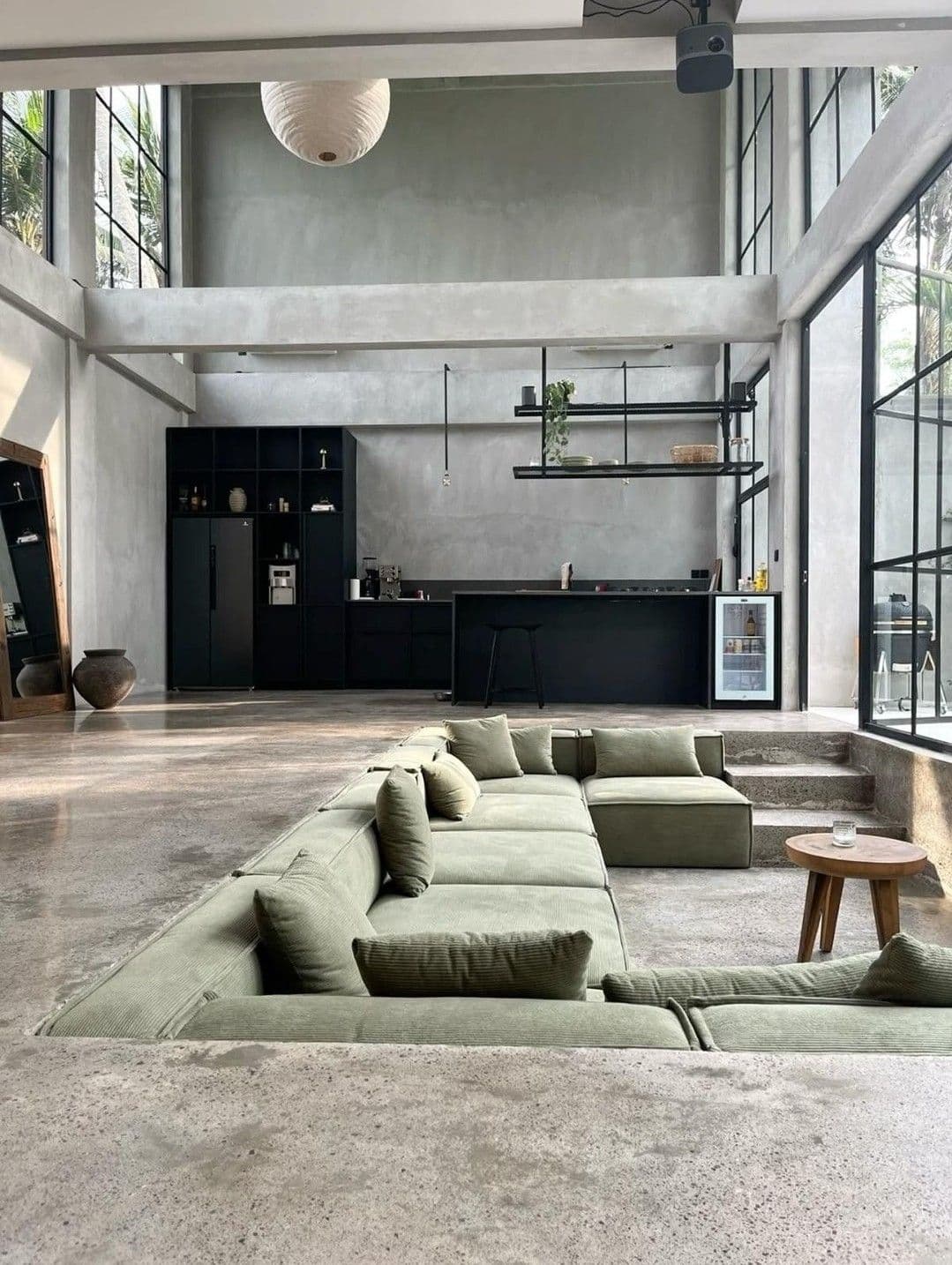 An interior with natural light, concrete walls, and large windows