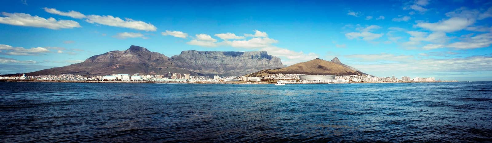 A wide view across Table Bay toward Cape Town, with Table Mountain's flat summit and neighboring peaks behind the waterfront