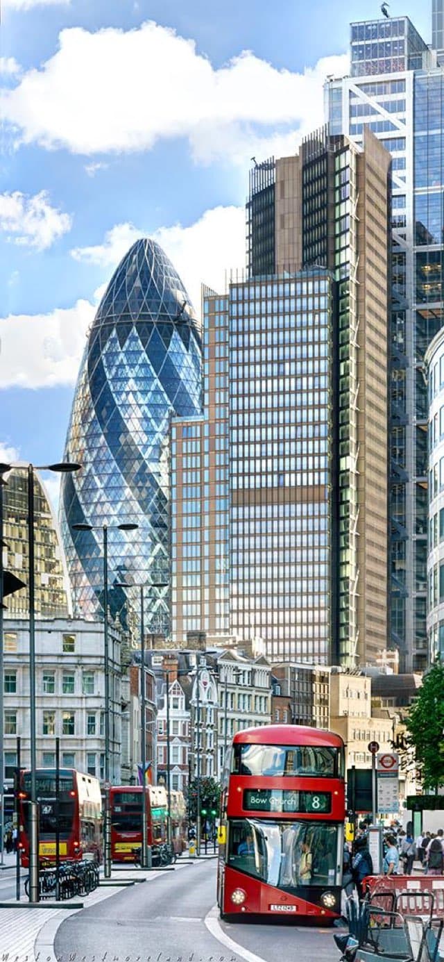 A London street with red double-decker buses and the Gherkin behind surrounding buildings